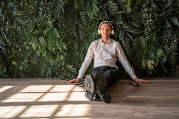 Mature businessman sitting on floor and listening to music