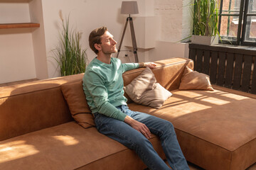 Mature man with eyes closed sitting on sofa at home