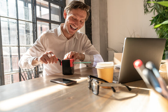 Happy businessman sharpening pencil with sharpener at desk
