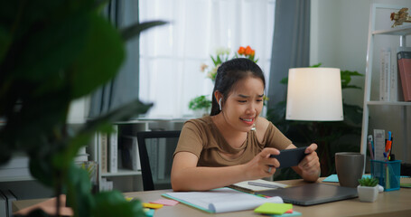 Young Asian woman with earphone playing a game on mobile phone