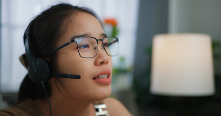 Young Asian woman wearing glasses using a laptop on a desk