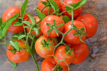 Fresh red tomatoes with green leaves on wooden floor shot from atop corner