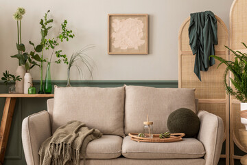Interior design of spring living room interior with mock up poster frame, beige sofa, wooden coffee table, plants in flowerpots, rattan sideboard and personal accessories. Home decor. Template.
