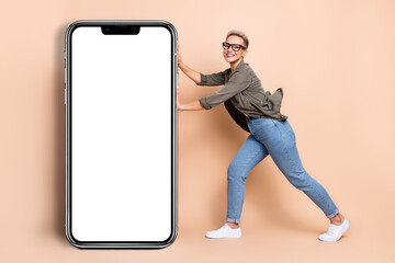 Full length photo of funny excited lady dressed khaki shirt holding big modern gadget emtpy space isolated beige color background
