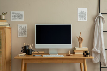 Creative composition of cozy office space with mock up poster frame, wooden desk, computer, rattan sideboard, books, black cup, pencils, ladder and personal accessories. Home decor. Template.