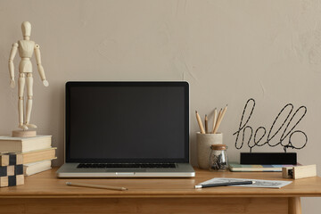 Aesthetic composition of simple office interior with wooden desk, computer, books, black sculpture, cup with pencils, brown wall and personal accessories. Home decor. Template.