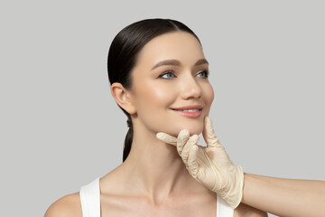 A beautiful girl makes an injection of botox, on a gray background