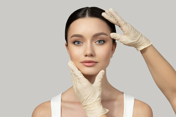 A beautiful girl makes an injection of botox, on a gray background