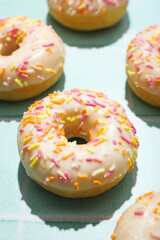White donuts with colored sprinkles on blue background, close up