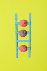 Stepladder and jelly candies on green background, top view
