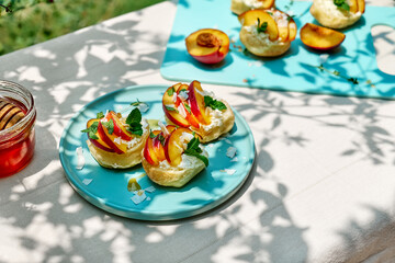 Mini sandwiches with cream cheese, nectarines, coconut, mint and honey. Delicious summer peaches toast, healthy lunch idea.