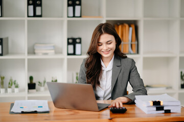 Beautiful woman using laptop and tablet while sitting at her working place. Concentrated at work..