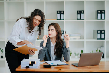 Businesswomen work and discuss their business plans. A Human employee explains and shows her colleague the results paper in modern office..
