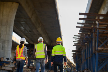 A team of civil engineers working on a road construction site with architects and industrial construction workers. Concept of an engineer team