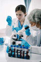 Team of biochemical research scientists working with a microscope for vaccine development in...
