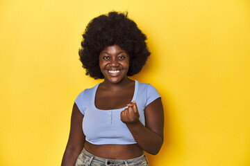 African-American woman with afro, studio yellow background pointing with finger at you as if...