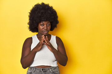 Fototapeta na wymiar African-American woman with afro, studio yellow background making up plan in mind, setting up an idea.