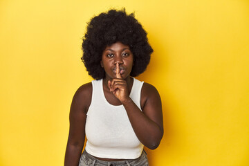 Fototapeta na wymiar African-American woman with afro, studio yellow background keeping a secret or asking for silence.