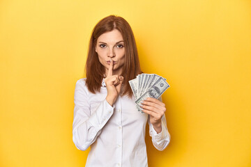 Redhead with dollar bills, cash in hand keeping a secret or asking for silence.