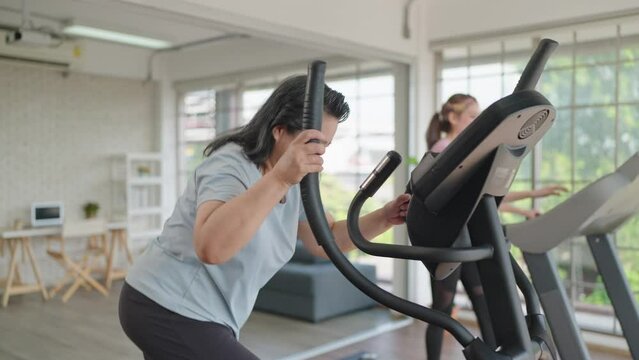 Happy elderly women and daughter give high five before having exercising on the machine together in living room at home. Elderly lifestyle, Famity activity concept