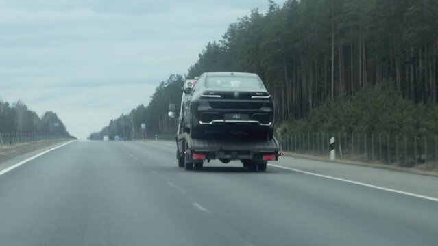 a car tow truck carries a car to a service on a highway in cloudy weather in spring. Copy space for text