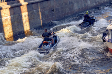 Men float on jet skis on the river. Friends ride an aquatic motorcycle along the canals and rivers of the city.