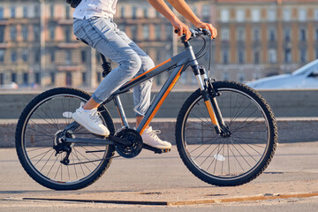 A young man rides a bicycle around the city, close-up.