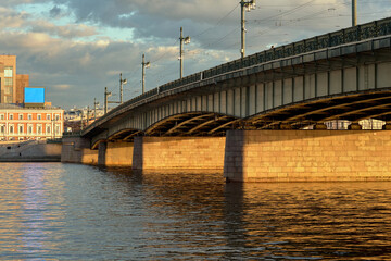 Reinforced concrete bridge across the big river of the old city at sunset. Drawbridge with beautiful street lamps.
