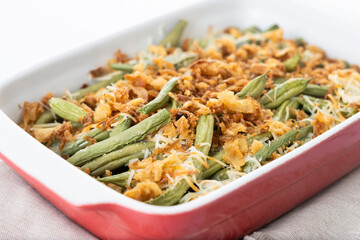 A traditional green bean casserole topped with French Fried Onions and cream of mushroom isolated on white background. Close up