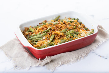 A traditional green bean casserole topped with French Fried Onions and cream of mushroom on white...