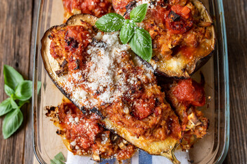 Stuffed eggplants with brown rice, tomato sauce and tuna filling in a glass casserole