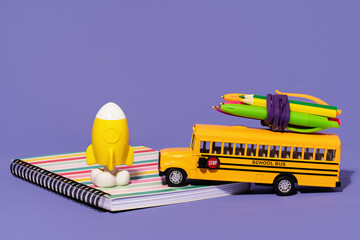 School bus with with pencils and pens on top on lilac purple background. Back to school. Delivery...