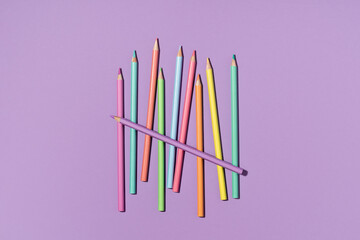 Colored pastel encils on lilac violet background. Back to School or drawing and creativity concept. Copy space. Top view
