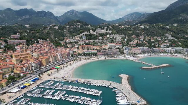 Plage des Sablettes beach in Menton France and old town with boat marina on the left, Aerial pan left shot
