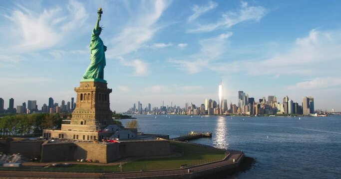 Aerial Helicopter Cinematic Passing View of the Statue of Liberty with Manhattan Skyline Cityscape. Panoramic View of New York City Skyscrapers and Jersey City Buildings on a Sunny Day