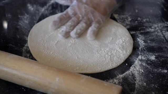 Italian chef preparing pizza dough and rolling on stone table strat flatten kneaded bread