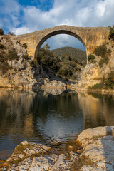Fototapeta na wymiar View of an ancient bridge Pont de Llierca in Catalonia, Spain. This beautiful bridge, paved with sandstone slabs, is in use since the 14th century.