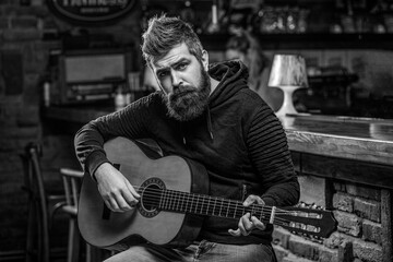 Fototapeta na wymiar Bearded guitarist plays. Play guitar. Beard hipster man sitting in a pub. Live music. Black and white