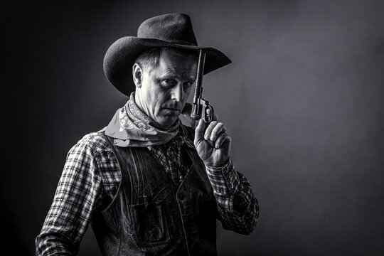 West, guns. Portrait of man wearing cowboy hat, gun. Portrait of a cowboy. American bandit in mask, western man with hat. Black and white
