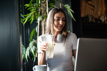 woman drinking coffee and lemonade in caffe, while working on computer