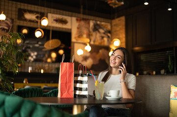 woman in a restaurant talking on phone after shopping