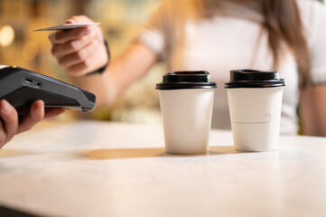 Close up of a woman paying coffe to go with credit card