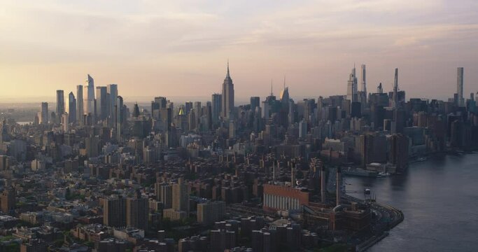 New York City Skyline at Sunset. Aerial Footage of Manhattan from a Helicopter. Panoramic View from the Side of East Village and Generating Station Power Plant on East River