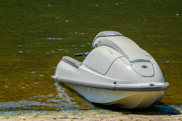 A white, plain and unmarked jetski with gray accents sits idle on an algae covered boat ramp...