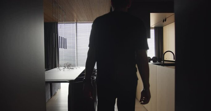 A man looks out the window into a apartment with an modern kitchen interior, The man walks through the kitchen and stops at the window. Modern Dinning room with wood and minimalist design.