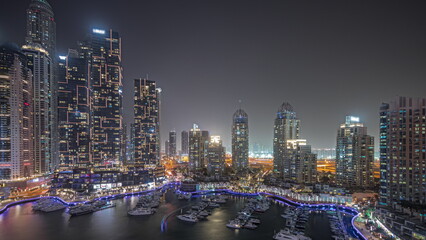 Fototapeta na wymiar Panorama showing Dubai marina tallest skyscrapers and yachts in harbor aerial night timelapse.