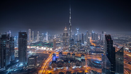 Panorama showing aerial view of tallest towers in Dubai Downtown skyline and highway night...