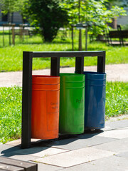 Naklejka premium Colorful metal recycle trash bins for paper, glass, plastic, general waste in public park urban area. Keep clean environment ecology. Garbage sorting containers Stop plastic pollution Waste management