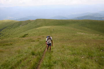 Mountain trekker: Tourist hiking high in the mountains.Man traveler with backpack is hiking in mountain.Traveling in nature. Baiului Mountains trails. Carpathians mountains in Romania. 