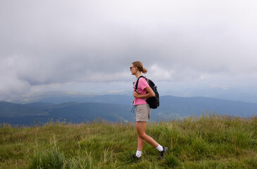 Woman is hiking in mountains in summer.Beautiful mountain landscape in Carpathians, Romania.Travel and tourism.Woman hiker is enjoying the mountain view.